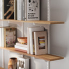 4 tiered wooden shelf with white metal bracket, displaying books and decor items, highlighting the natural wood grain, clean edges, and sturdy bracket support.