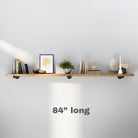 A minimal 84 inch extra long shelf styled with books, art, greenery, and ceramic decor, showcasing a long horizontal layout with industrial pipe brackets.