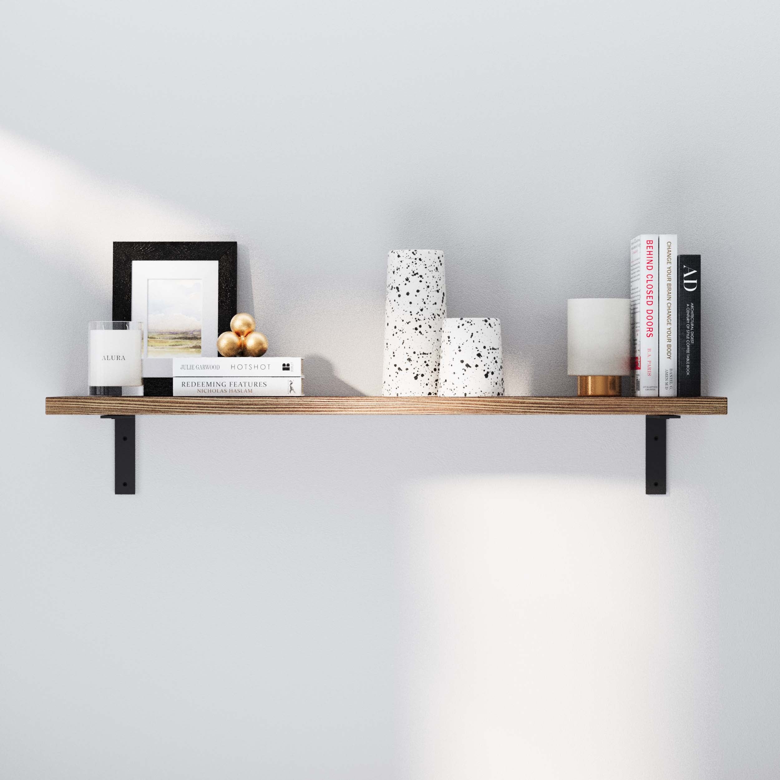 A single hanging shelf wall mounted on a white wall, holding decorative items like books, candles, and ceramic pieces. Highlights the shelf's versatility and elegant simplicity.